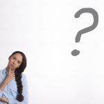 Une personne avec le doigt sur le menton et un point d'interrogation sur un mur blanc.